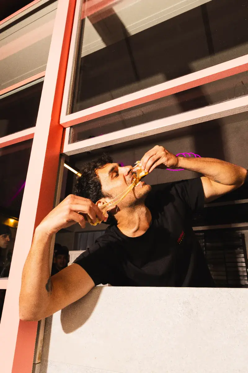 Cliente comiendo una empanada apoyado en la ventana del local